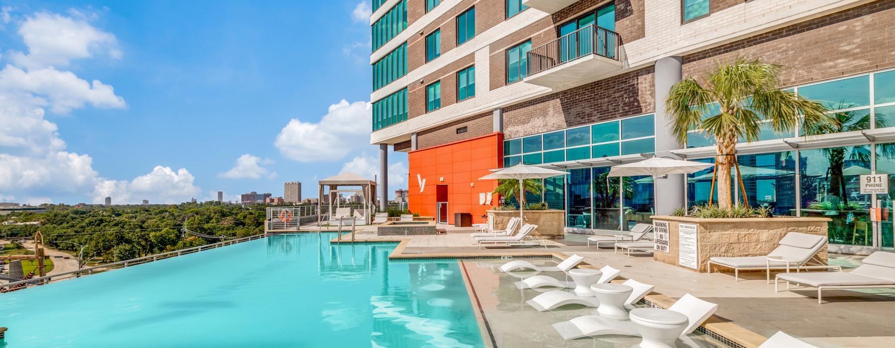 a pool with lounge chairs and a building in the background