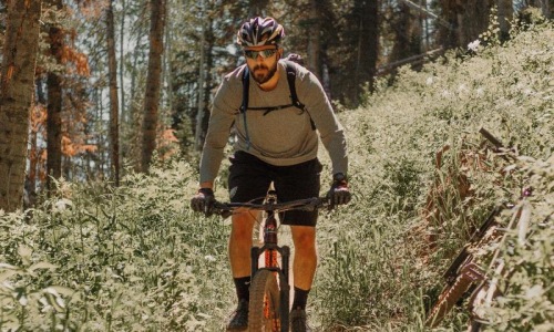 A beautiful community at the heart of all your passions man riding a bike on a trail in the woods
